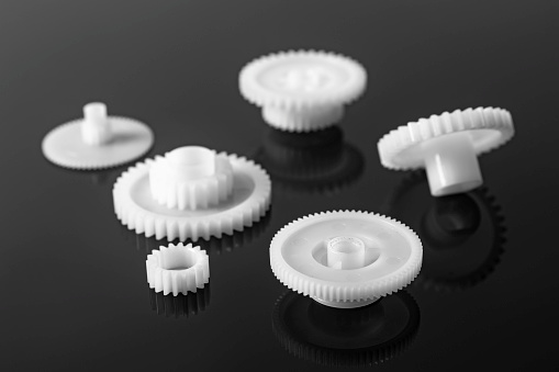 White plastic gears on a black background.