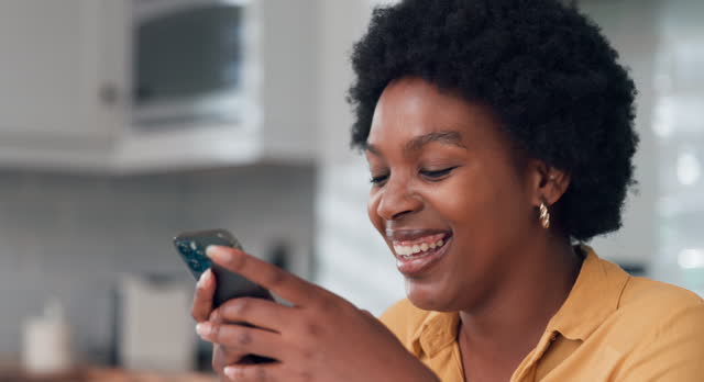 Young woman using smartphone at home. African american girl looking at mobile phone in her room.
