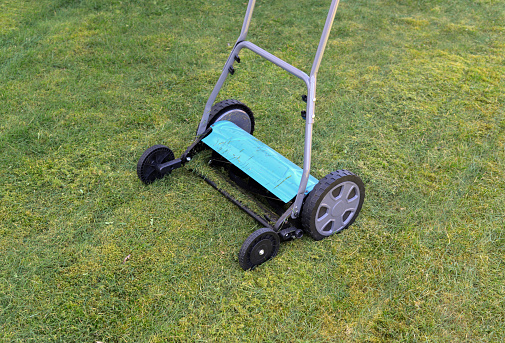 Closeup of a mass produced push reel mower on a cut lawn.