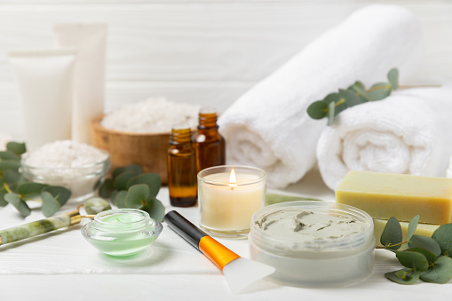Beautiful spa composition on a wooden background with eucalyptus leaves. Beauty and fashion spa concept with body cream, scrub, mask, essential oil and sea salt.Cosmetic product. Copy space.