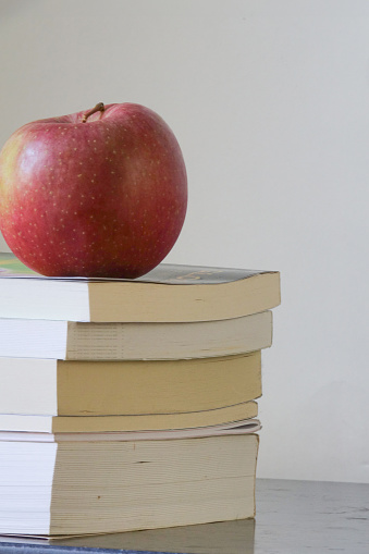 A single apple rests on top of a pile of books