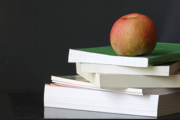 A pile of books topped with a fresh apple