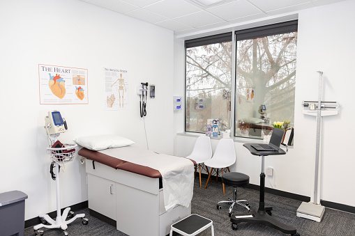 An empty examination room well-furnished with medical equipment is ready for the next patient.