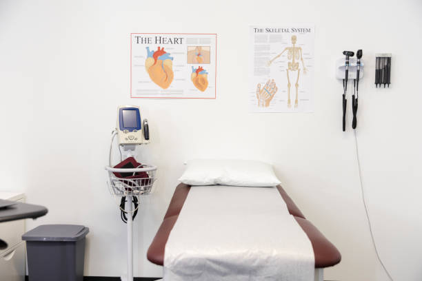 A clean, empty room in a doctor's office with an examination table and various pieces of medical equipment.
