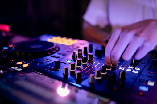 Close-up of the hands of DJ working using mixing table in a club