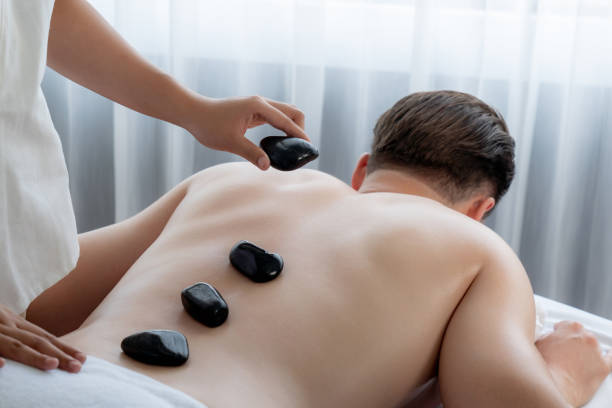 hot stone massage at spa salon in luxury resort. quiescent - lastone therapy massaging stone shiatsu - fotografias e filmes do acervo