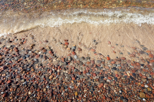 The wave of the Baltic Sea and the beautiful water-polished pink stones on the shore.