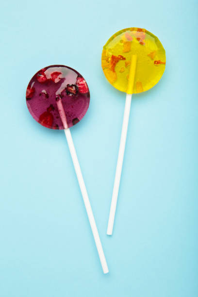 istock Red and yellow sweet lollipops with berries on blue background. Space for text 2099652530