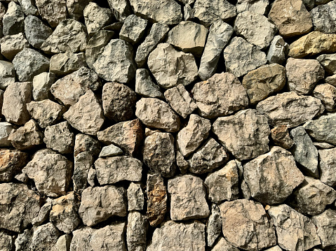 Texture of a rock wall built with the ancient dry stone technique. All stones are fitted together without concrete.