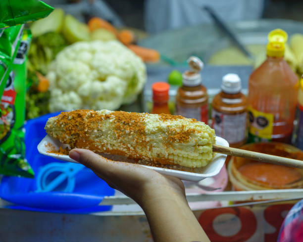 Mexican woman preparing a boiled corn, typical Mexican street food. Food stall. Elote.