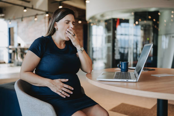 istock Sleepy pregnant woman at work yawning 2099665896