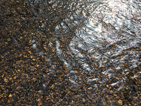 Water surface in nature with small stones. Clear stream surface and small stones at the bottom