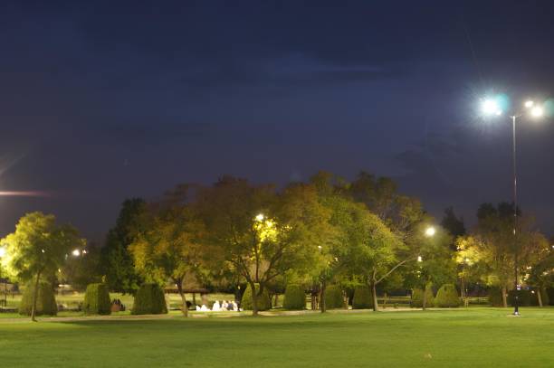 istock A park at night with a group of people sitting on benches 2099671794