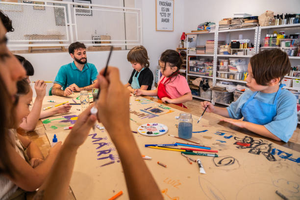 Kids painting on cardboard poster during paint class at workshop