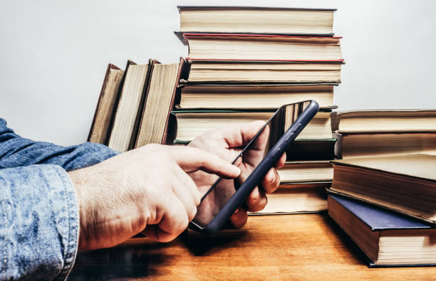 istock Photo of male hands with smartphone and books stack. 2099678276