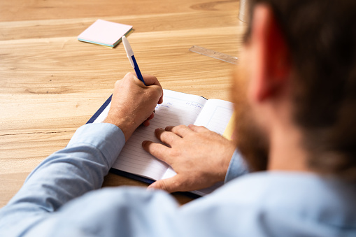 Close-up of man writing notes in notepad