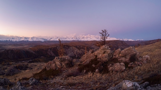 Evening panoramic mountain gorge on the background of sunset snowy mountains. Hiking path. Spectacular view of distant giant mountains.Perfect autumn image for wall, screen, artwork.