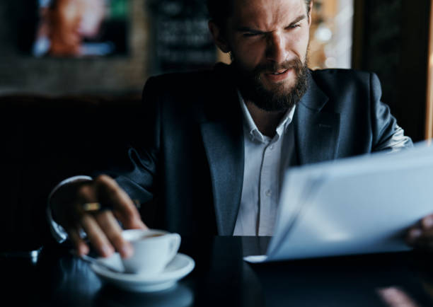 istock business man sitting at a table in a cafe documents work official coffee cup 2099698872