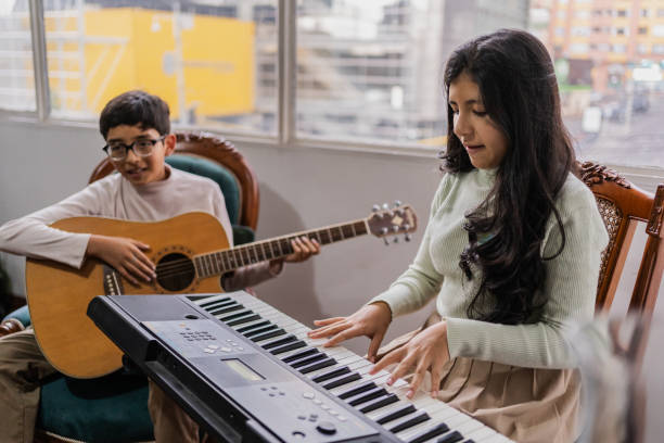 istock Siblings playing guitar synthesizer at home 2099702571