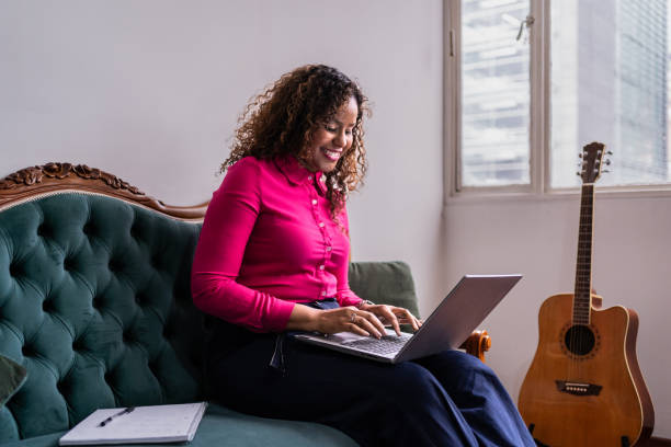 istock Mid adult woman using laptop at home 2099703100