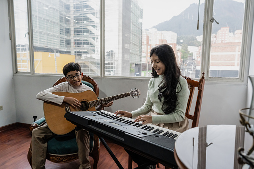 Siblings playing guitar synthesizer at home