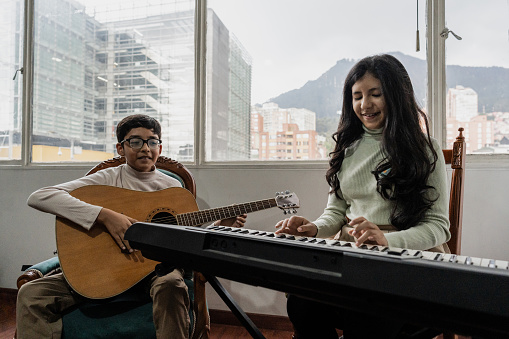 Siblings playing guitar synthesizer at home