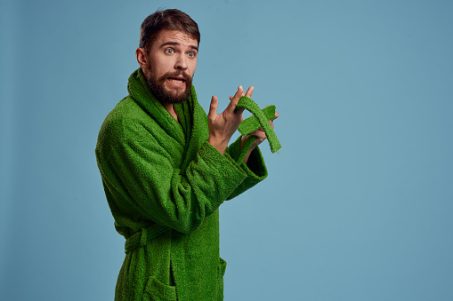 Bearded man in green robe with belt on blue background cropped view of emotion. High quality photo