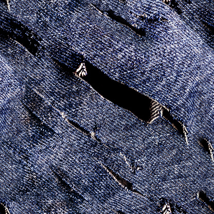 Seamless texture photo of blue colored cutted torn denim or jeans material.