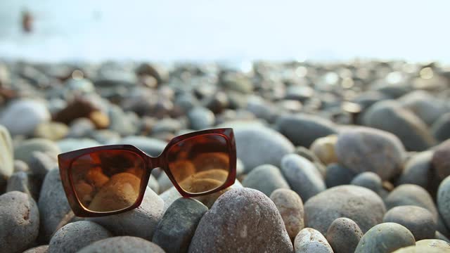 A pair of sunglasses is laying on a rocky beach