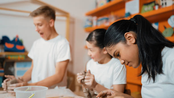 istock Boy modeling bowl of clay while cute asian girl working on dough. Edification. 2099737441