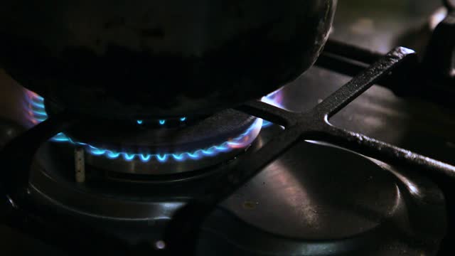 A hand lighting a match and igniting the stove in the kitchen, close-up