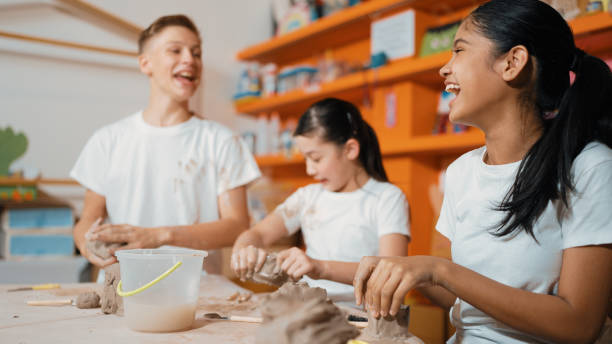 student playing with friend while put the clay on shirt at class. edification. - top of the class foto e immagini stock