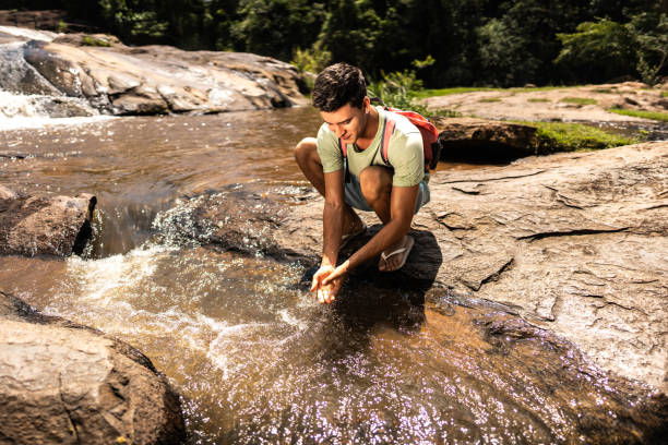 istock Young man washing hands on river at a mountain during eco tourism 2099747700
