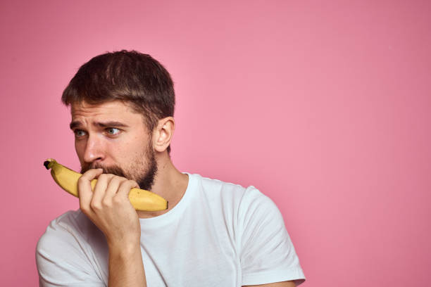 istock bearded man with banana in hand on pink background fun emotions model 2099749270