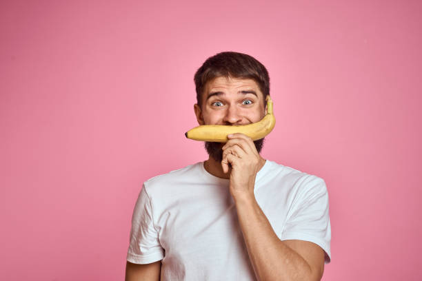 istock bearded man with banana in hand on pink background fun emotions model 2099757461