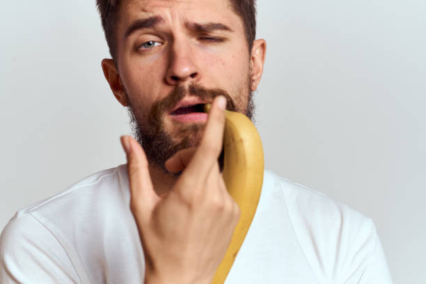 istock Cheerful man with a banana in his hands on a light background fun emotions Cropped view Copy Space 2099757727