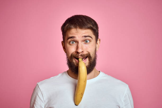 istock bearded man with banana in hand on pink background fun emotions model 2099773571