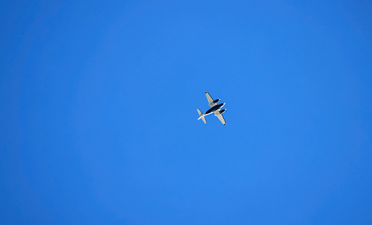 Ground-based photograph of a twin-engine plane under a blue sky