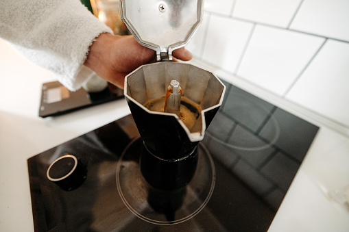 Man prepares morning coffee in domestic kitchen at home