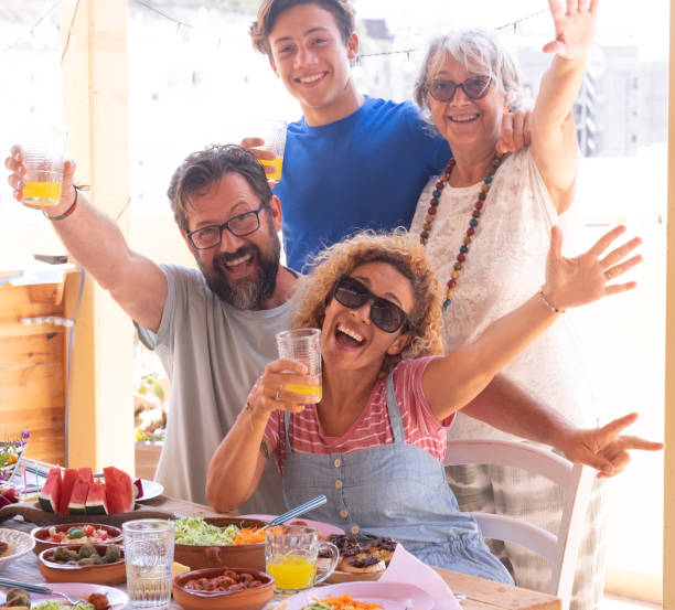 istock Cheerful multi generation family have fun in outdoors enjoying brunch together gesturing to the camera. Senior woman with son, daughter-in-law and nephew. 2099795891