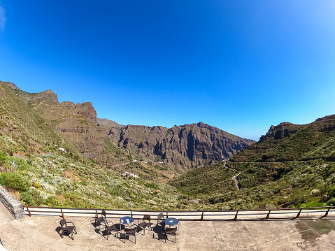 Aerial scenic view from a cafe on the narrow winding mountain road in remote village Masca, Teno mountain massif, Tenerife, Canary Islands, Spain, Europe. Empty chairs on panoramic terrace