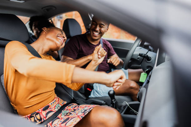 Friends dancing inside a car during a road trip