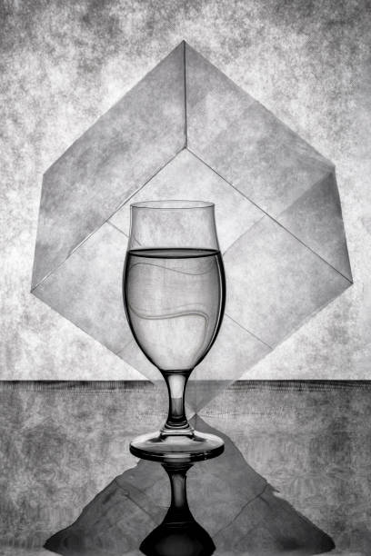 Still life with a glass of liquid and a cube