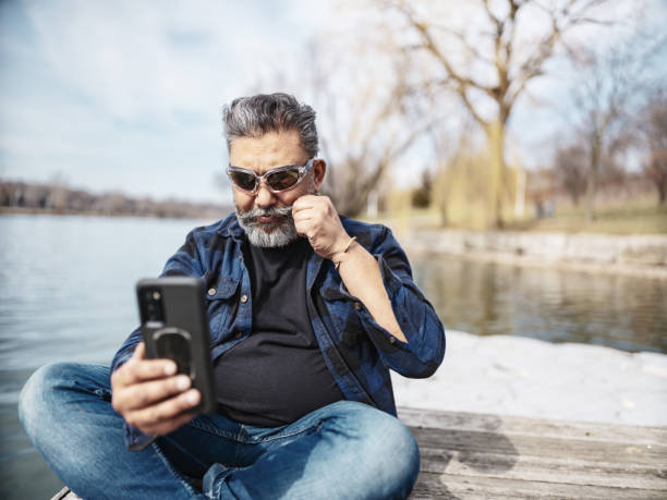 Mature Indian man taking a break cycling on the lake pier stock photo