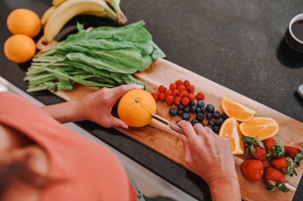 istock High angle view of woman cutting orange into half on chopping board 2099808708