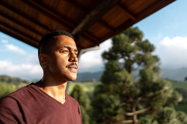 Young man looking away enjoying balcony farm inn