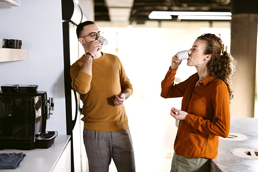 Man and a woman are drinking coffee in the kitchen