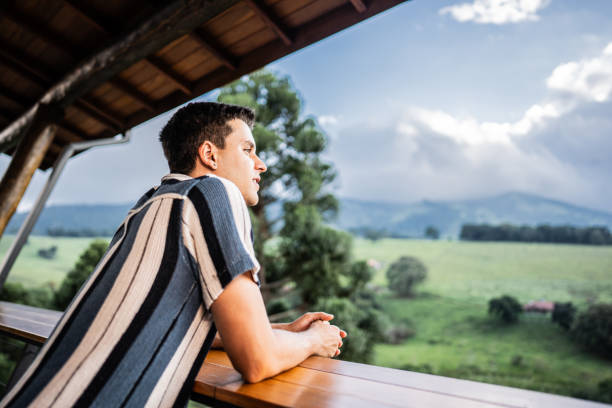 istock Young man relaxing looking at view on balcony farm inn 2099824501