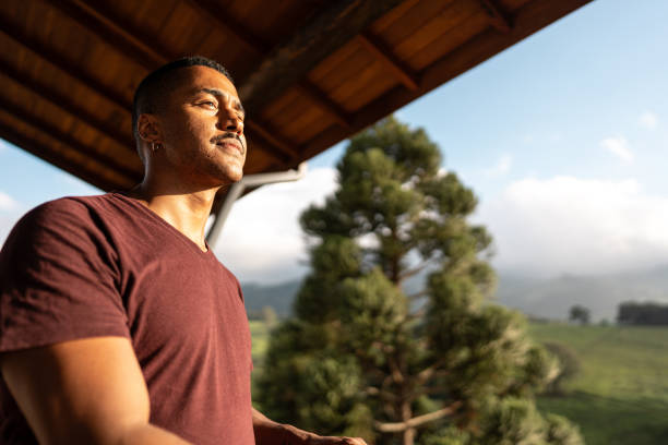 Young man looking away enjoying balcony farm inn