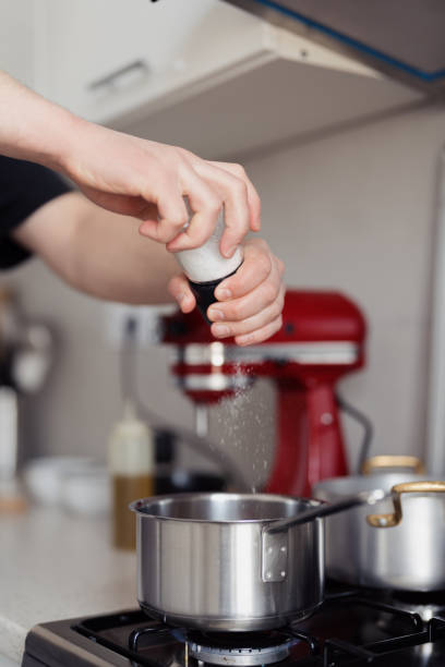 istock Home cooking preparation, adding salt to boiling pot on stove 2099846434